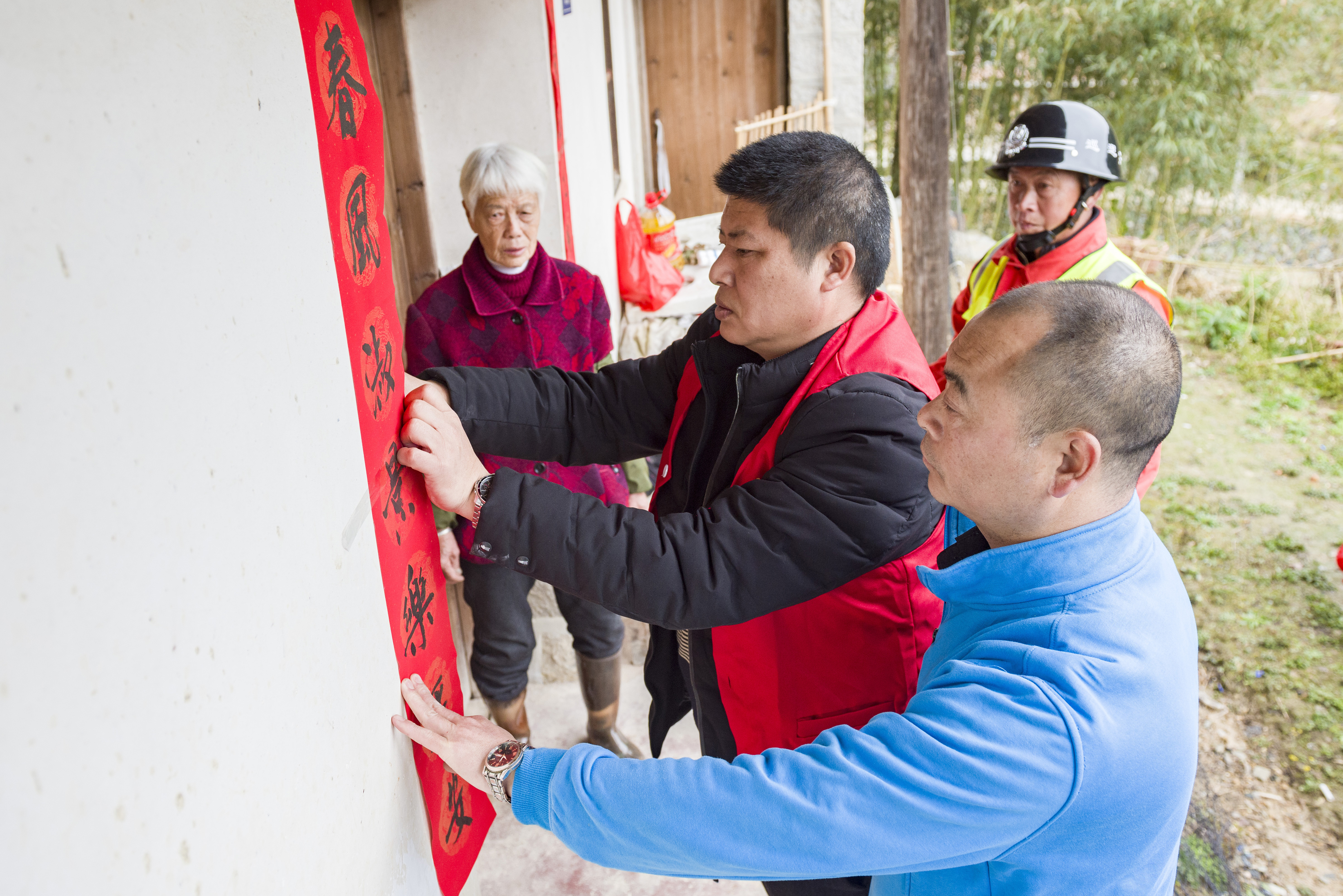 1月25日，猛湖片區(qū)“黨建+”鄰里中心志愿者給老人貼春聯(lián)。（許華森 攝）.jpg?x-oss-process=style/w10